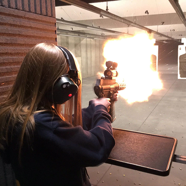 girl shooting rifle in a shooting range that she did not win in a gun webinar