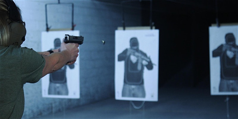 lady shooting a gun in an indoor gun range